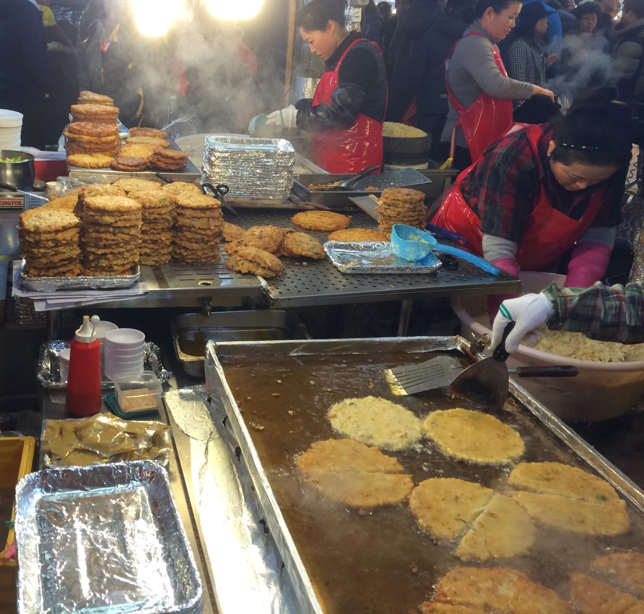 Vendors fry bindaetteok pancakes at Gwangjang Market in Seoul.
